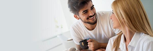 Seguros de Ahorro - Pareja joven feliz y enamorados en pijama, utilizando la tablet tumbados en el sofa de casa buscando seguros de ahorro Seguros de Ahorro - Pareja joven feliz y enamorados en pijama, utilizando la tablet tumbados en el sofa de casa buscando seguros de ahorro